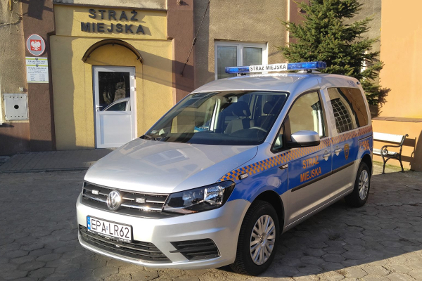 srebrny dostawczy samochód Straży Miejskiej stojący bokiem przed siedzibą Straży Miejskiej w Pabianicach
